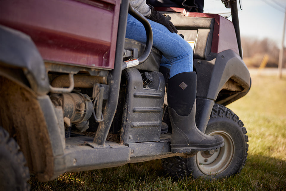 Woman riding a 4-wheeler with Chore muck boot on farm