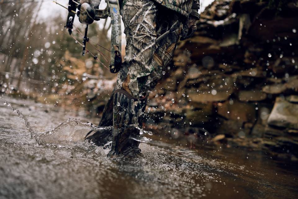Man steering green and yellow John Deer tractor wearing Men's Harvester Mid Rubber Muck Boots