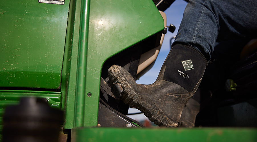 Man driving tactor wearing Muck Edgewater Classic Boots