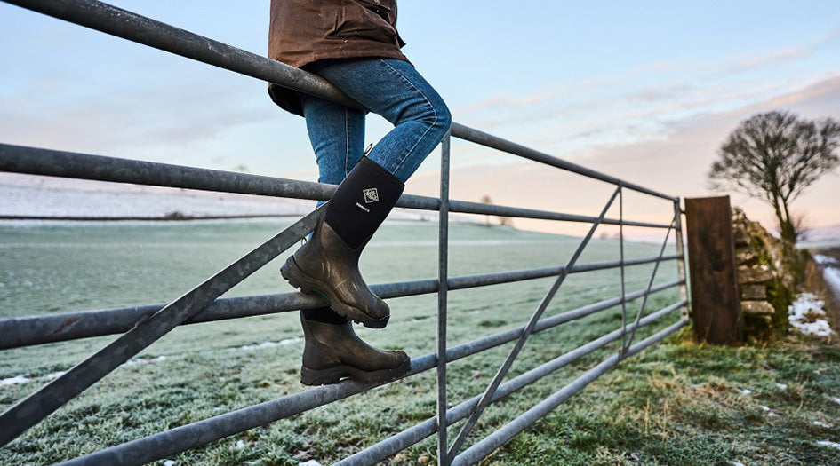Person sitting on gate wearing Muck Derwent Boots