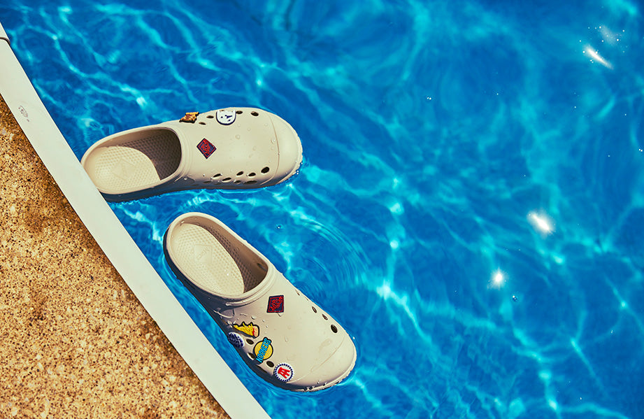 Muckster clog floating in a pool with Barstool Sports flare pins.