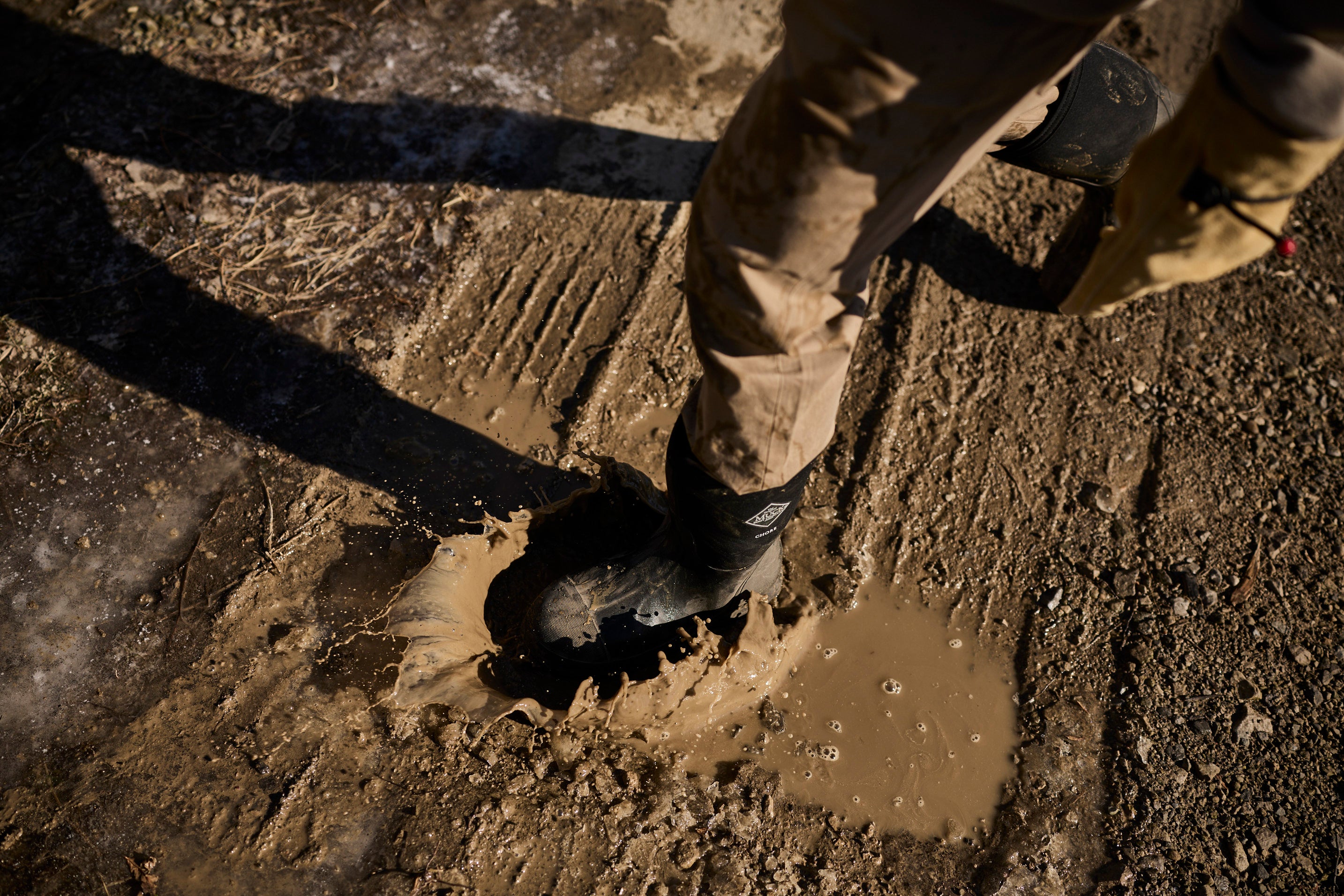 Man waking on muddy dirt road in Muck Boots