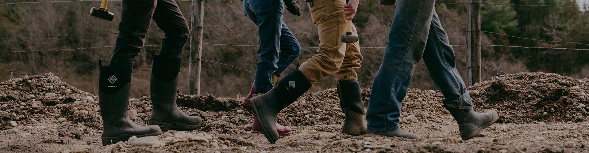 Four people walking towards a dirty job in their Muck Boots