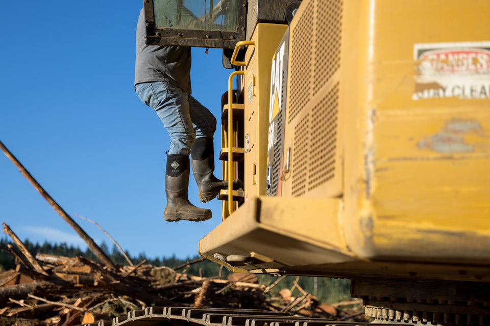 Man climbing into tractor wearing Muck Boots