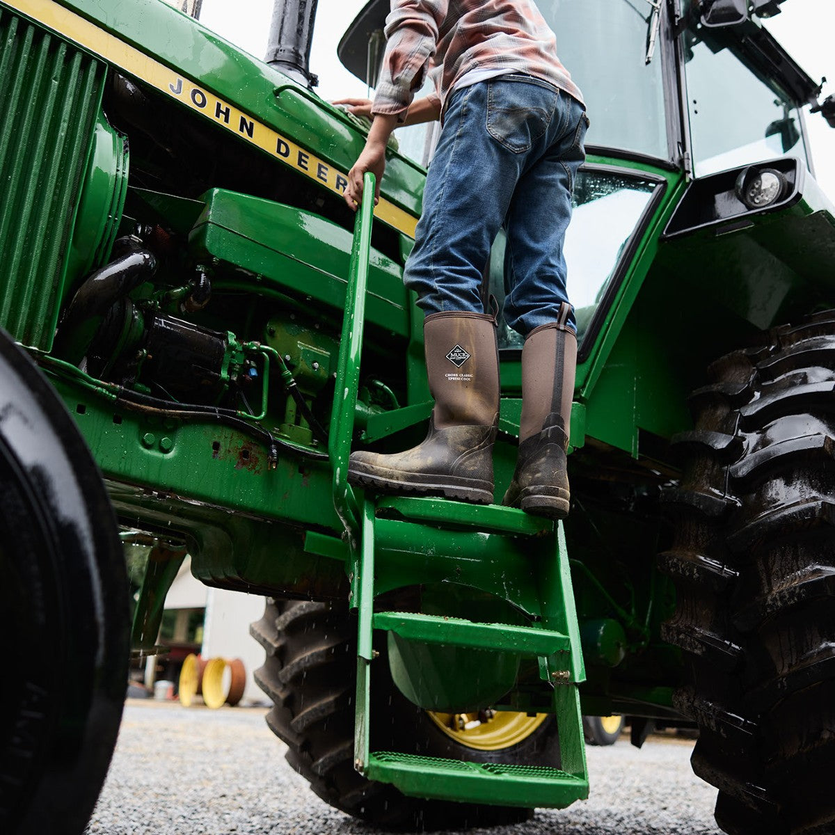 Man climbing into John Deere tractor wearing Muck Boots