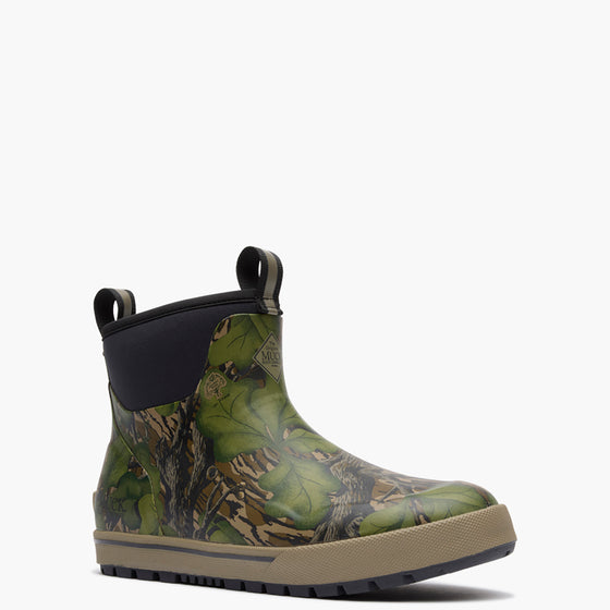 Green camouflage Muck boot with a black sole on a white background