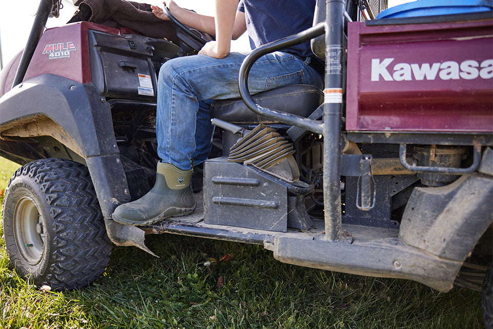Man sitting on tractor wearing green ankle height muck boots