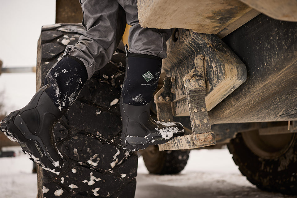 Man stepping up onto utility truck in snowy winter setting