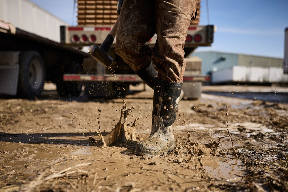 Man walking through a muddy jobsite with mud splashing
