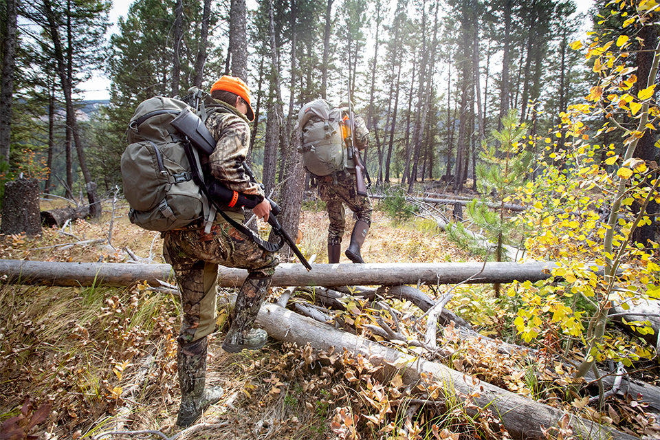 Two hunters trekking through a creek in waterproof muck boots