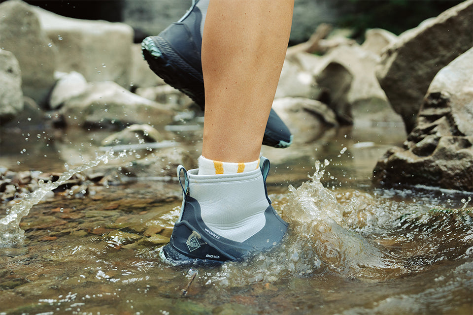 Muck boot submerged in water while walking in a creek
