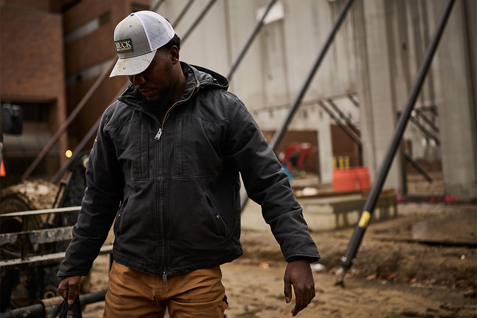 Man on a jobsite wearing a Muck logo hat