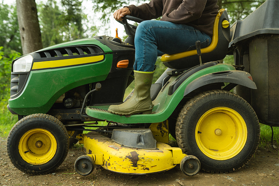 Man steering green and yellow John Deer tractor wearing Men's Harvester Mid Rubber Muck Boots