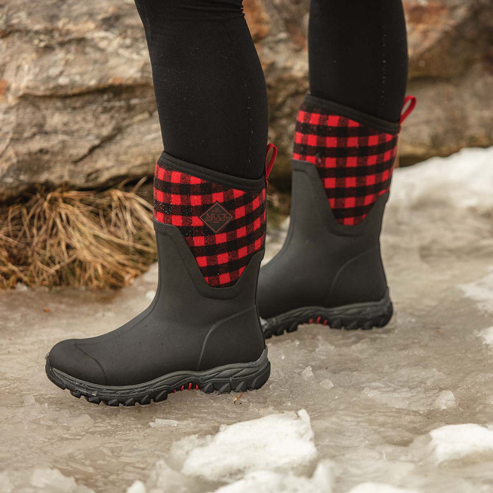 Black boots with red plaid pattern on a snowy ground