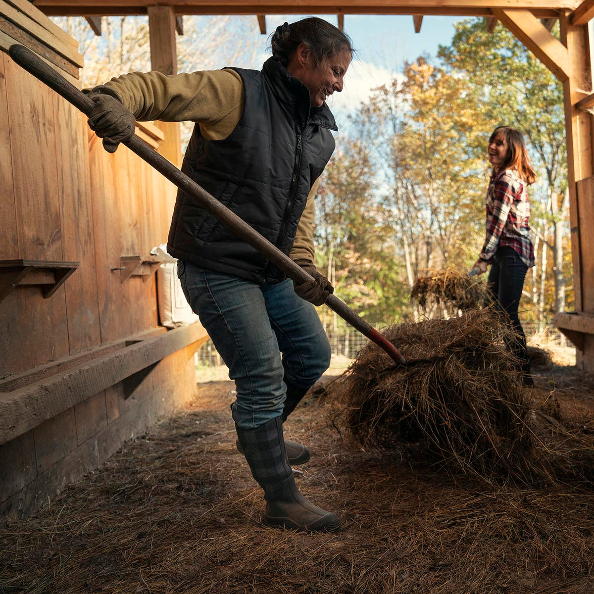 Two people working with hay in a rustic outdoor setting wearing Women's Hale Tall in Black Grey Plaid
