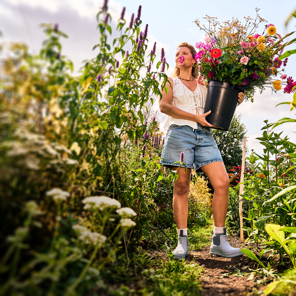Woman holding a bucket of flowers in a garden