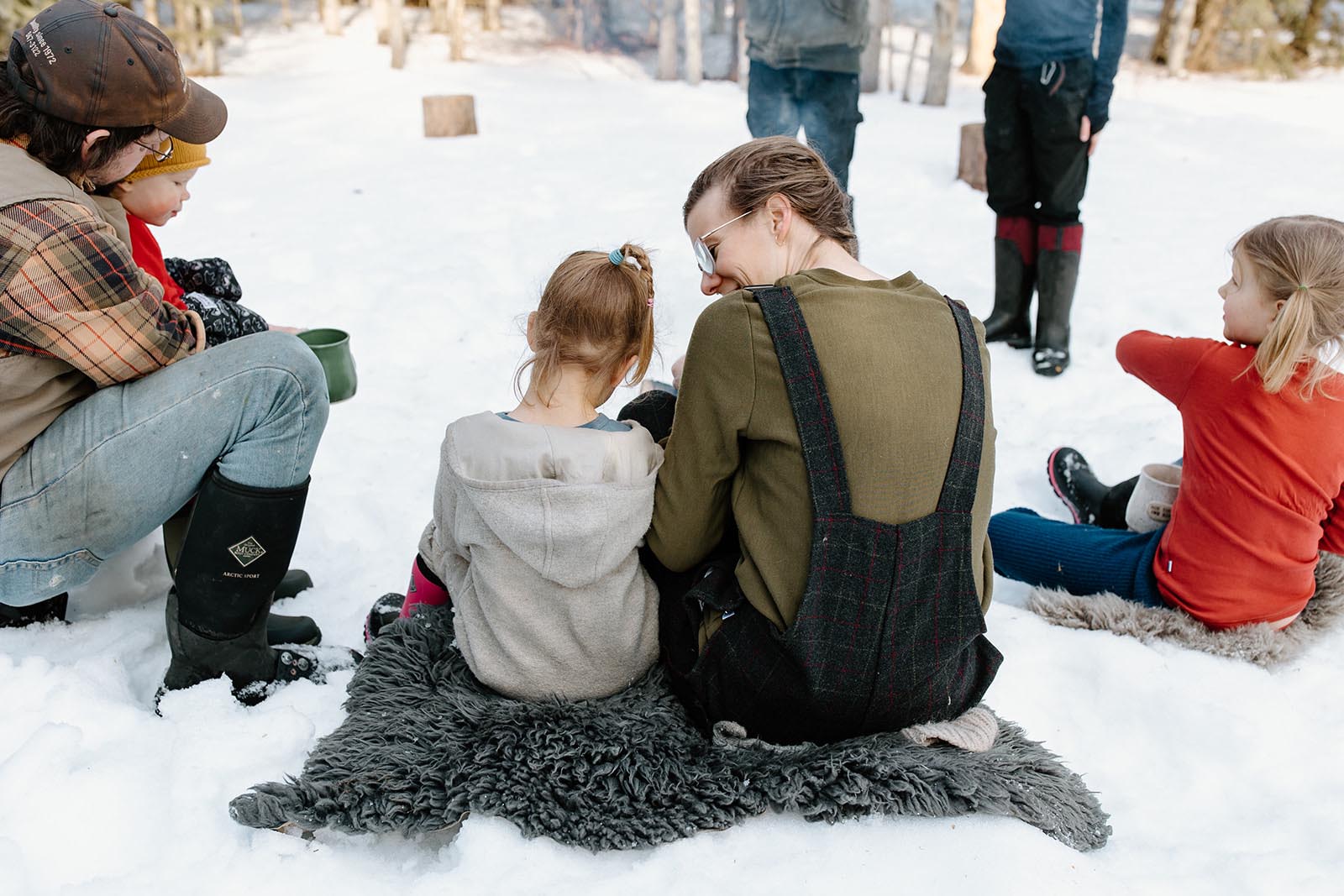Kate Schat and her family sitting on a blanket in the snowy Canadian outdoors.