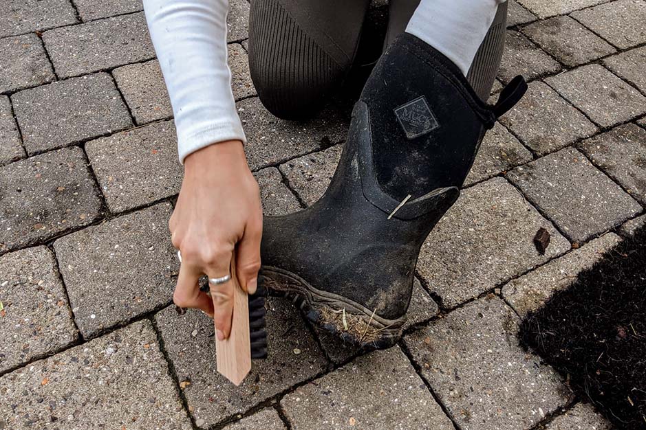 Brushing dirt of her Muck Boots with a brush