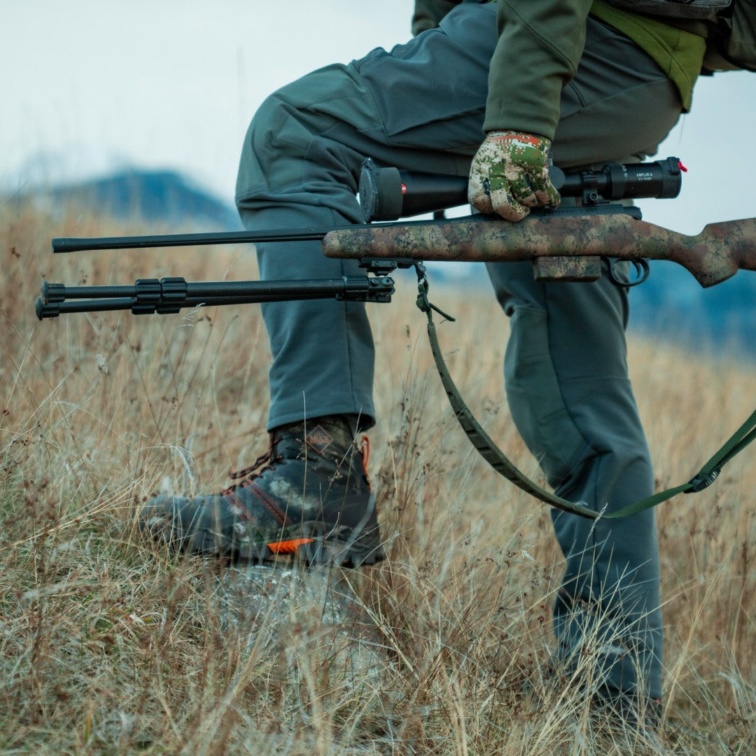 Hunter holding rifle wearing Muck Alpha Pursuit Boots
