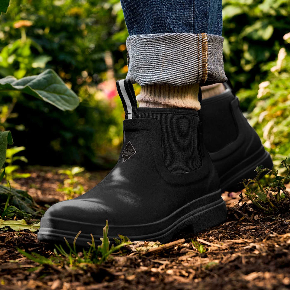 Black rubber rain boots worn outdoors in a garden setting