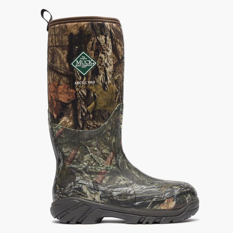A single Muck Boots Arctic Pro snowmobile boot with a detailed woodland camouflage pattern, featuring a green and white logo patch on the upper shaft, set against a plain light gray background.
